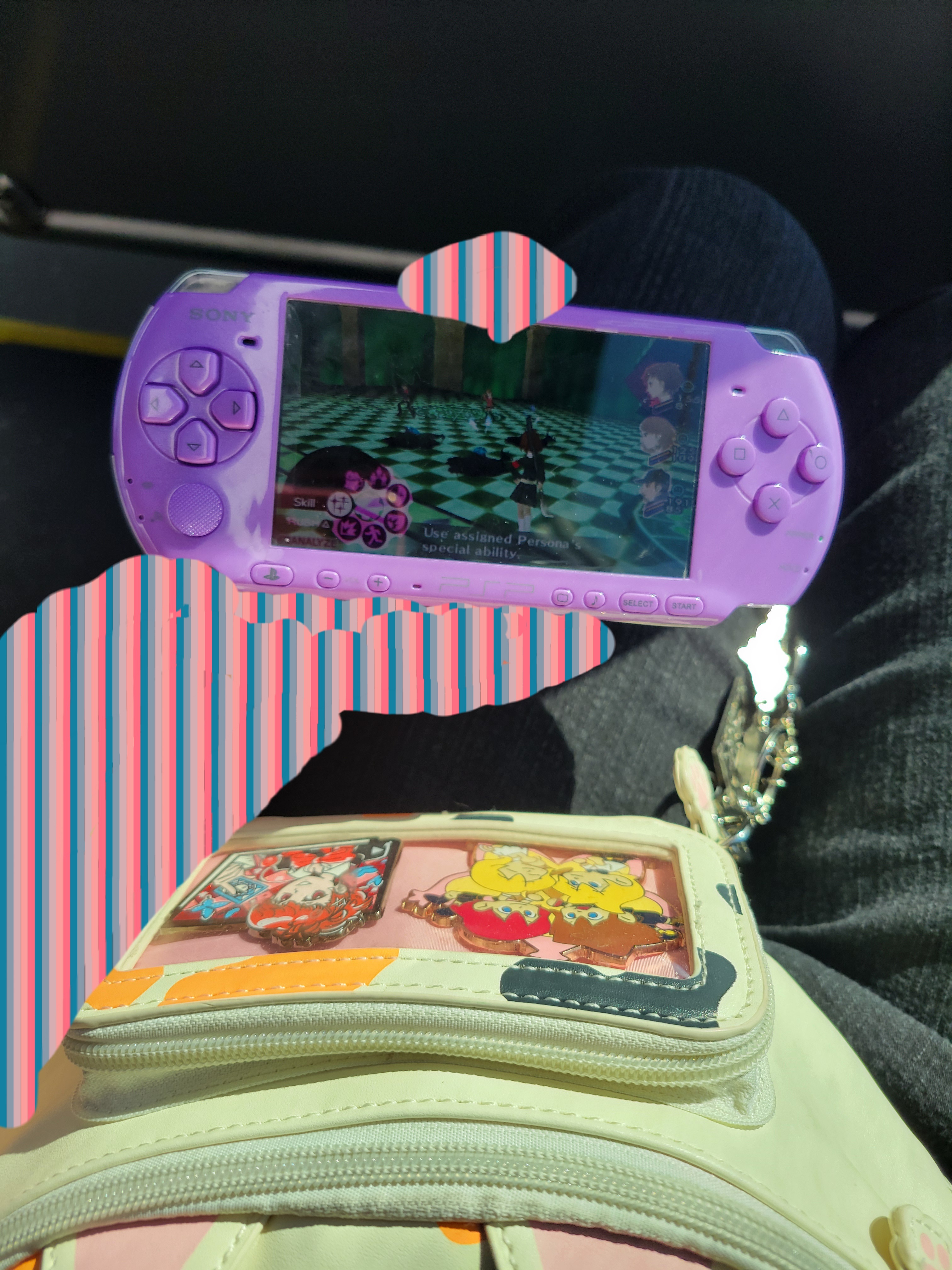 Fanny cat with a hand holding psp playing persona 3 portable behind it.